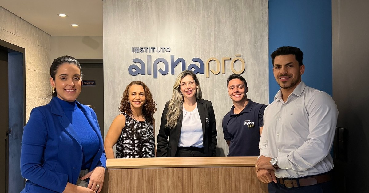 Equipe do Instituto AlphaPró na recepção da clínica, diante do letreiro na parede